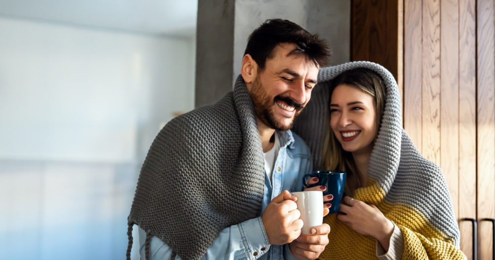 Paar sitzt eingekuschelt mit warmen Getränken, bleibt gesund durch die kalte Jahreszeit.